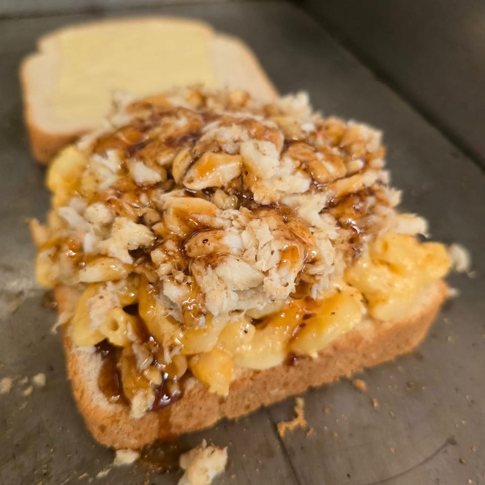 Seafood mac and cheese on toast, drizzled with sauce, from Men In The Kitchen.